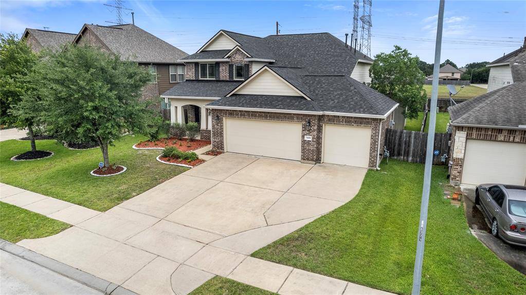 This two-story traditional home boasts a charming brick and stone façade, complemented by a well-maintained lawn and a spacious three-car attached garage.