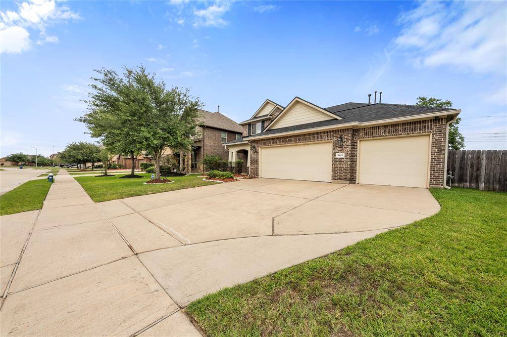 This two-story traditional home boasts a charming brick and stone façade, complemented by a well-maintained lawn and a spacious three-car attached garage.