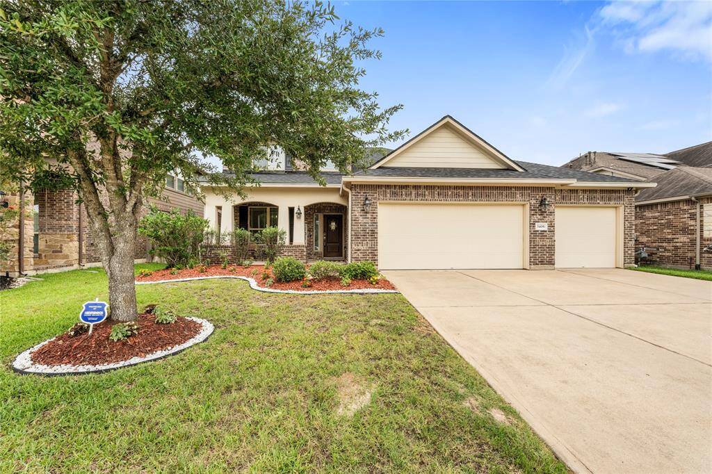 This two-story traditional home boasts a charming brick and stone façade, complemented by a well-maintained lawn and a spacious three-car attached garage.