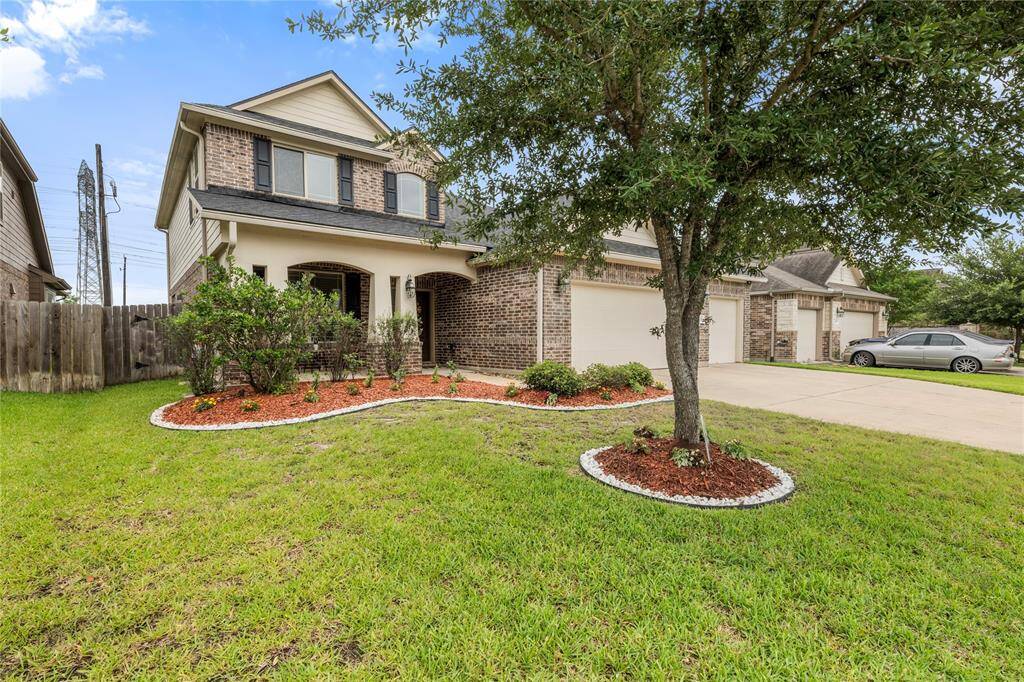 This two-story traditional home boasts a charming brick and stone façade, complemented by a well-maintained lawn and a spacious three-car attached garage.