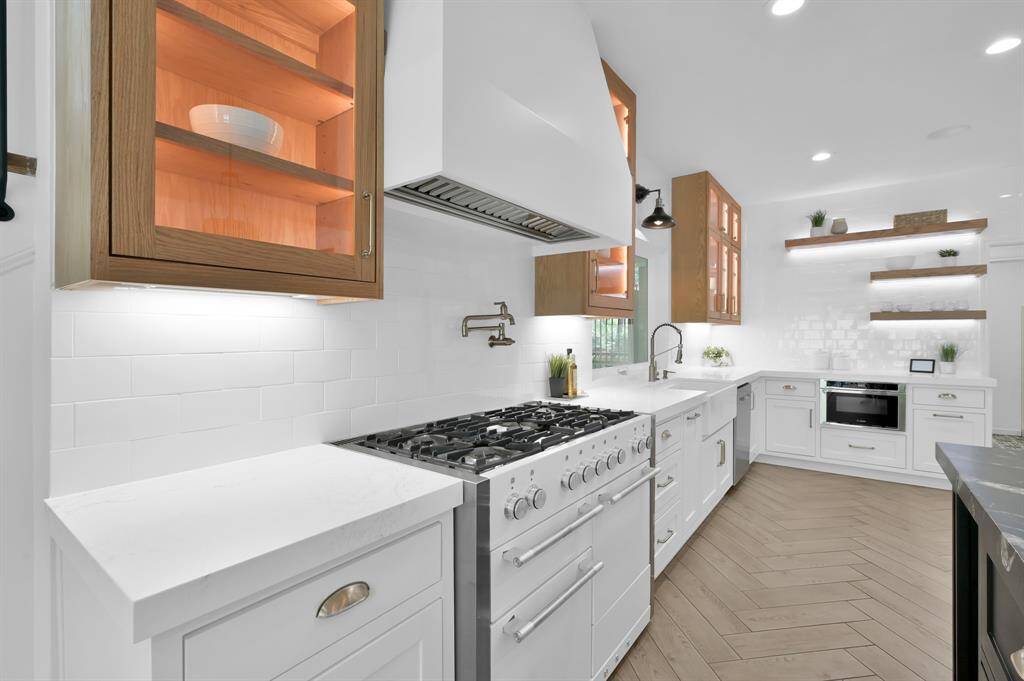 Notice the specialty gas range with double ovens and a pot filler.  Built-in microwave as well.
