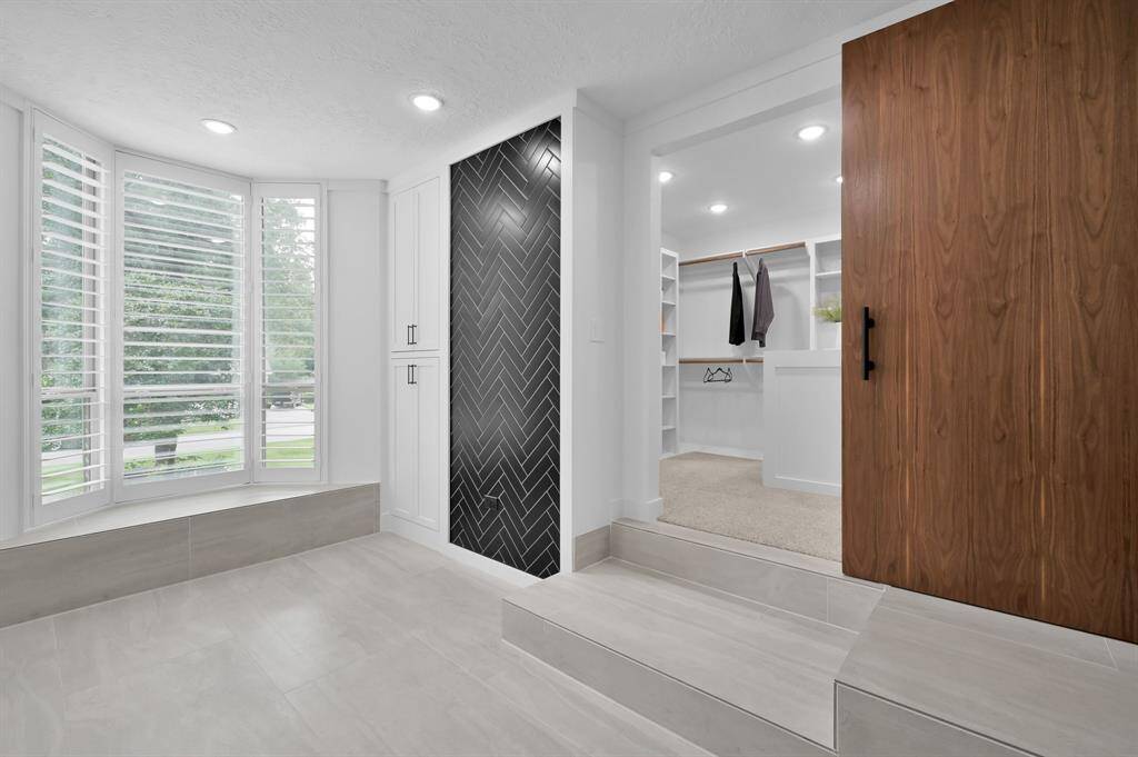 This bathroom features a modern design with sleek black tiles, a floating vanity with dual sinks, and touch lighted mirrors.