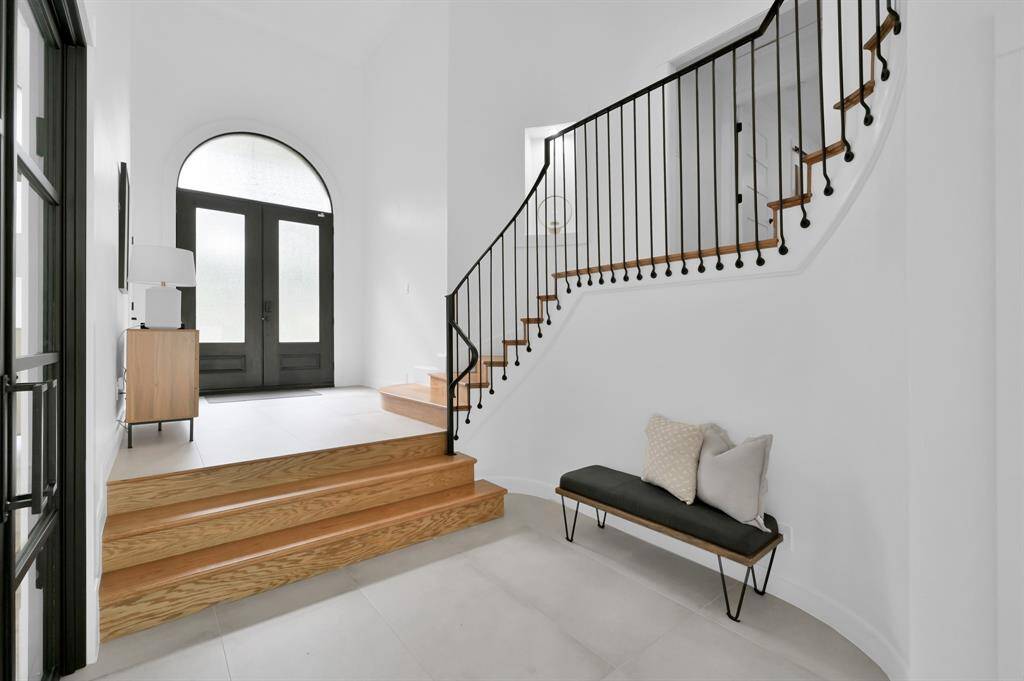Modern design touches include black iron and natural wood throughout the home. The door to the primary suite is shown at mid-stair level.