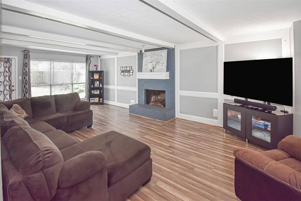 This spacious living room features stylish flooring, a cozy fireplace, and a large window that brings in natural light.