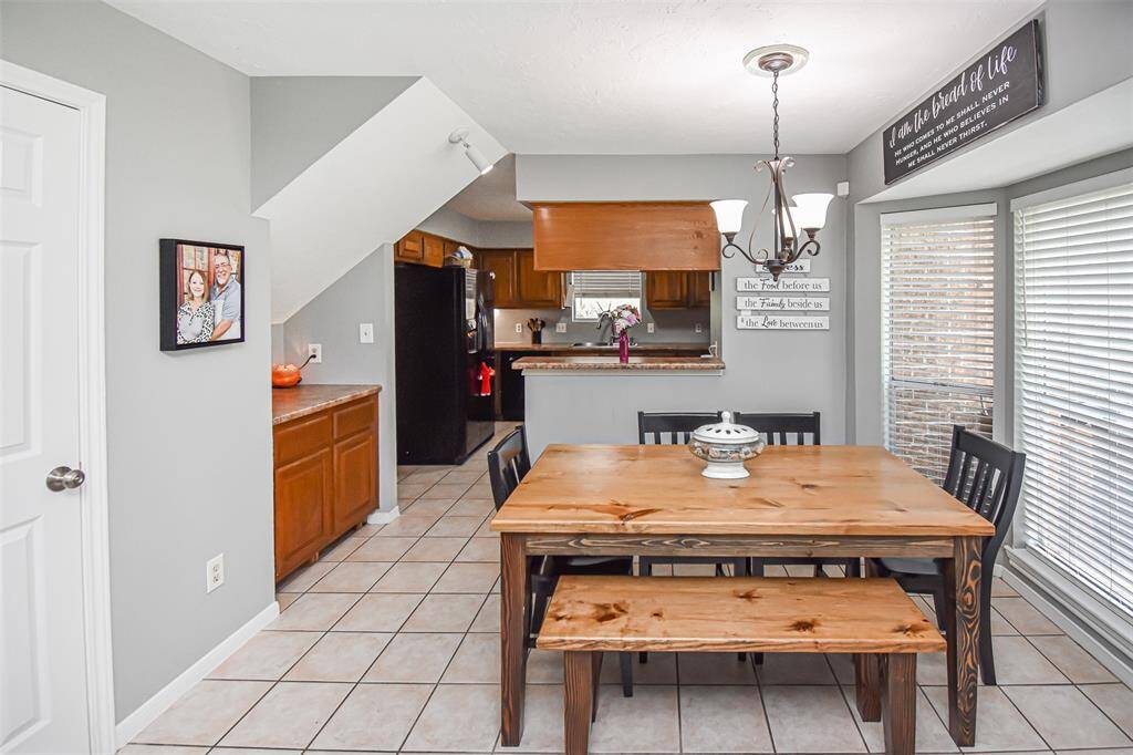 This cozy dining area, adjacent to a kitchen with warm wood cabinets. Large windows allow natural light to fill the space, and a modern light fixture adds charm. The layout is open and inviting, perfect for family gatherings.
