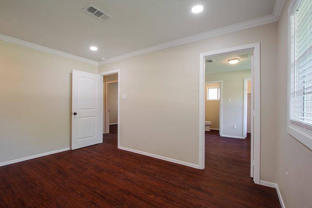 Bedroom with hardwood floors, and twodoor entrance.