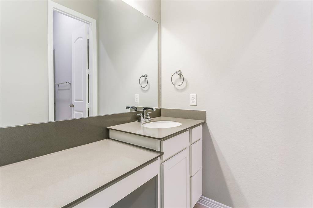 Another view of the Jack and Jill bathroom that offers beautiful white cabinetry and luxurious large gray countertops!