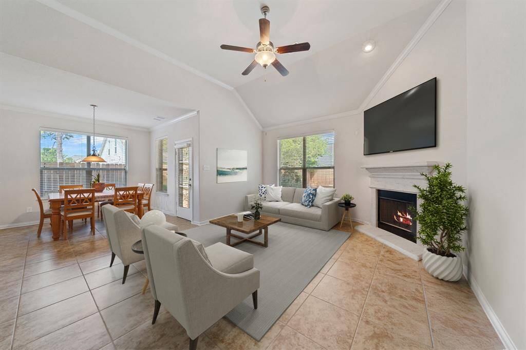 Virtually Staged: Stunning living room with tile floors, a high vaulted ceiling, crown molding details, a ceiling fan, large windows welcoming plenty of natural light, and a gorgeous fireplace with mantle.