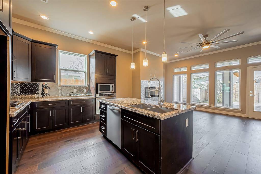 This kitchen has recessed lighting, a stainless steel dishwasher and pendant lighting over the bar. Double sinks are located within the island.