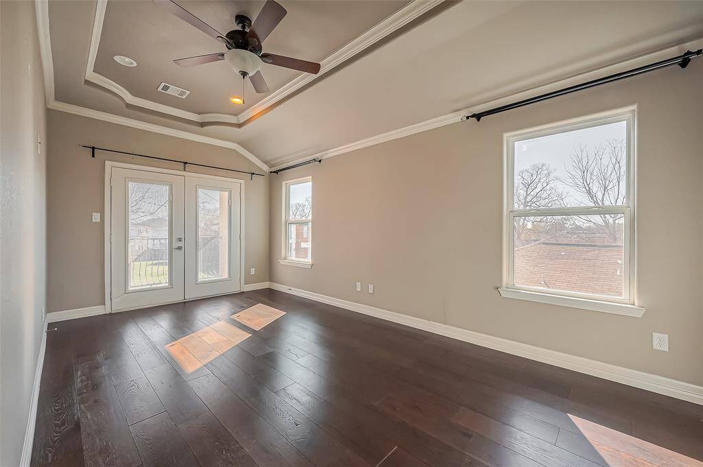 This large primary bedroom has a recessed ceiling along with crown molding and recessed lighting.