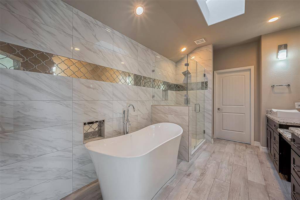 Welcome to the primary bathroom with a beautiful white soaker tub to help you relax after a long day.