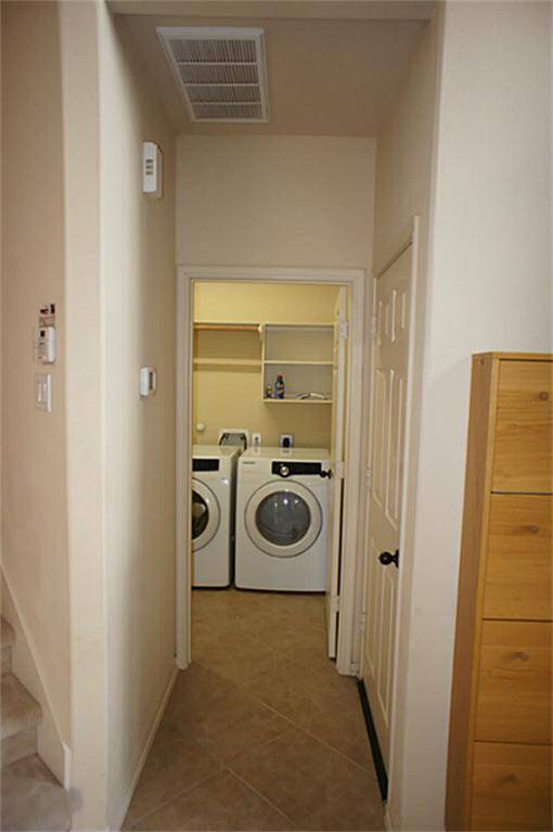 Hallway leads into the utility room, located downstairs next to the entryway from the garage, at the foot of the stairs.
