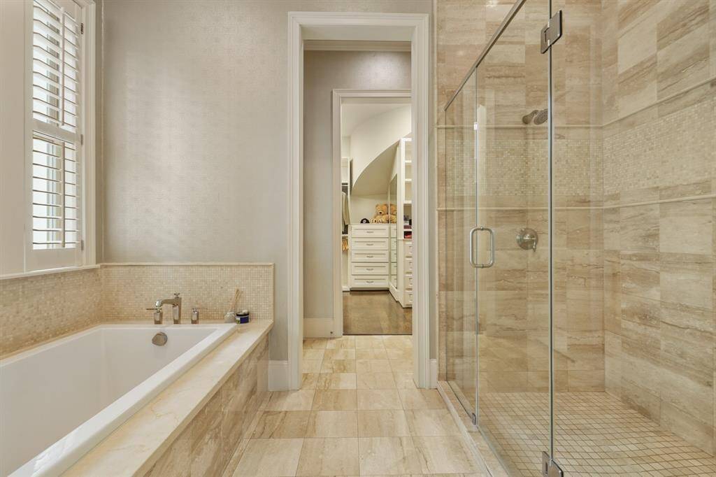 Luxurious master shower featuring elegant tilework and a sleek glass enclosure.