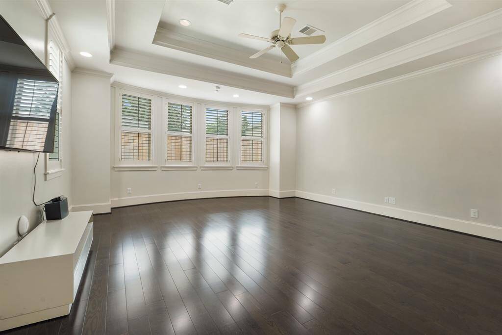 Luxurious master bedroom featuring elegant recessed ceilings and abundant lighting.