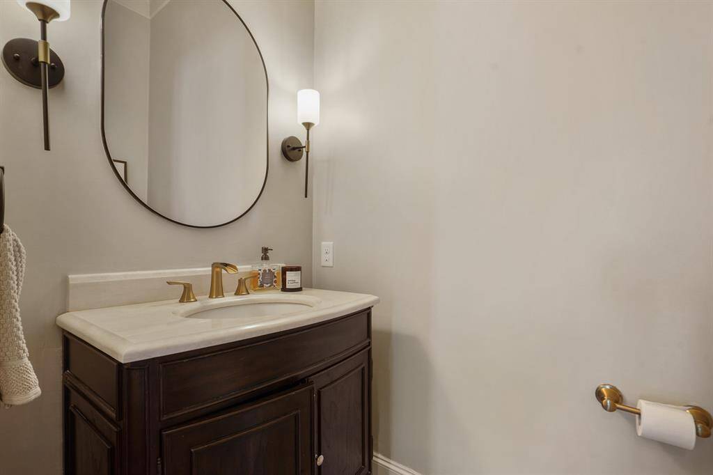 Elegant powder room featuring a sleek vanity, stylish fixtures, and warm lighting for a welcoming touch.
