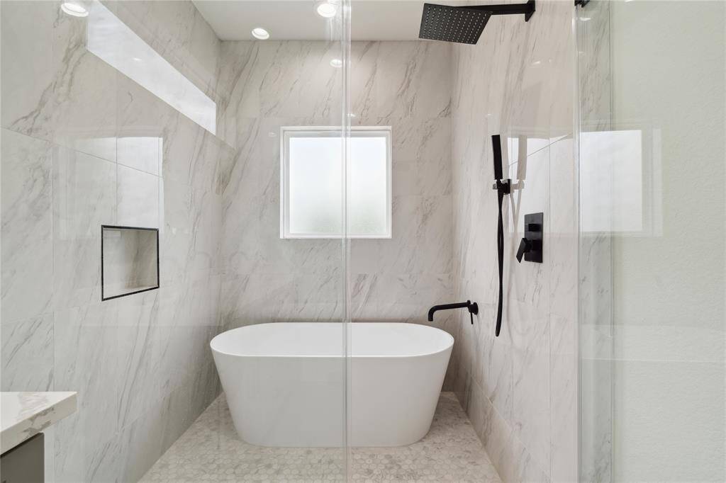 The spacious shower and tub combination offers a serene retreat, complete with a large window for natural light and an oversized shampoo niche for added convenience. It’s a perfect balance of comfort and luxury