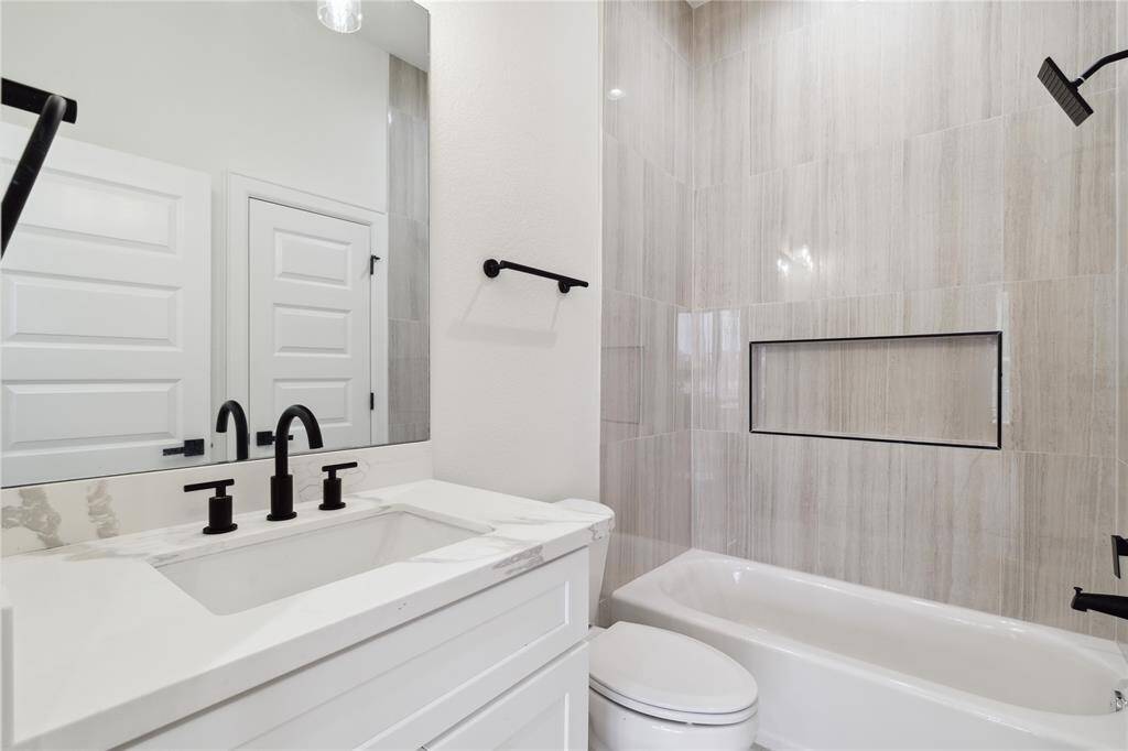The secondary bedroom’s ensuite bathroom mirrors the luxurious finishes found throughout the home, offering a stylish, spa-like retreat with high-end fixtures and design details. Perfect for guests or family.