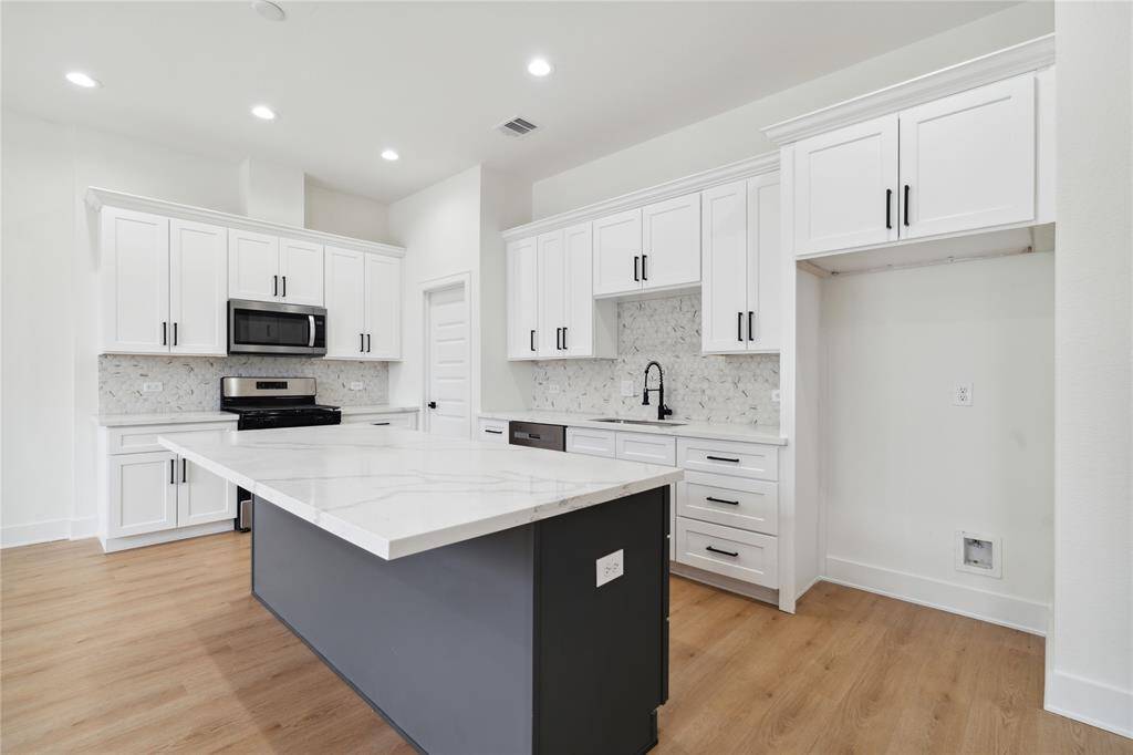 This spacious kitchen features a stunning quartz island that’s perfect for entertaining or everyday meals. Clean lines, modern finishes, and open sightlines make it the true centerpiece of the home