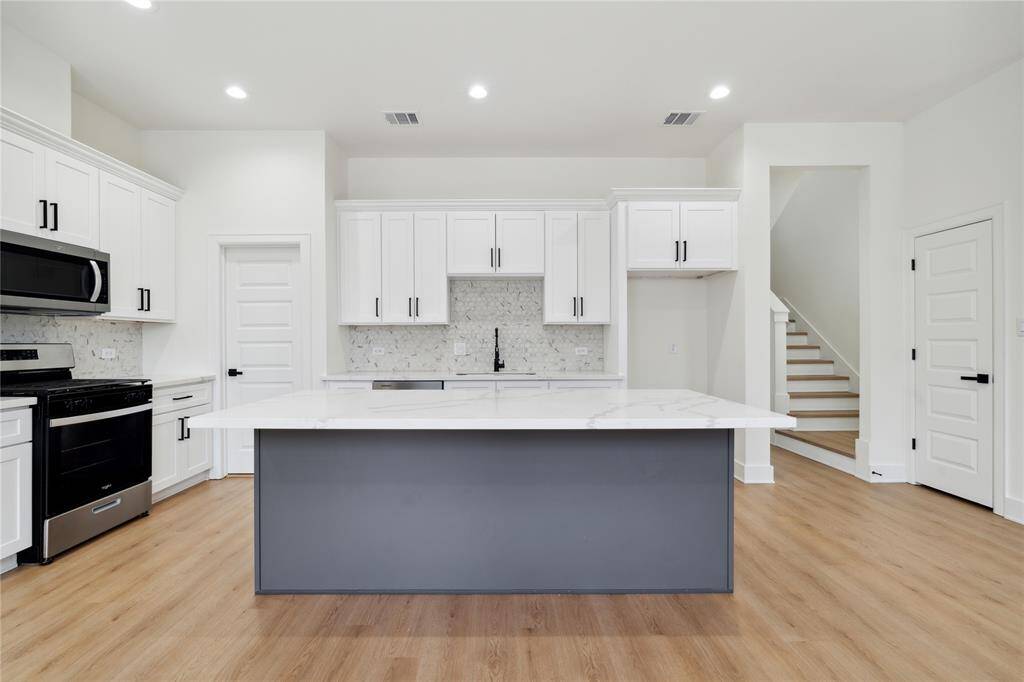 The oversized quartz island comfortably seats four, making it ideal for casual dining or hosting friends. With ample counter space all around, meal prep and entertaining are a breeze
