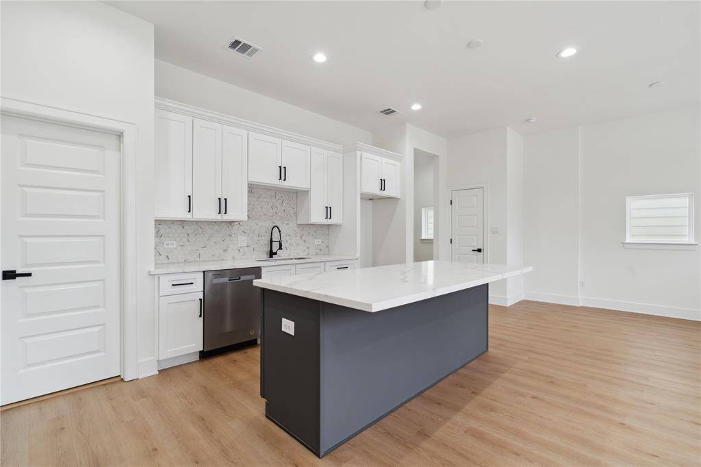 The gray accent island creates a striking contrast against the white cabinets, adding depth and modern flair to the kitchen’s design. It’s a bold yet balanced feature that elevates the entire space
