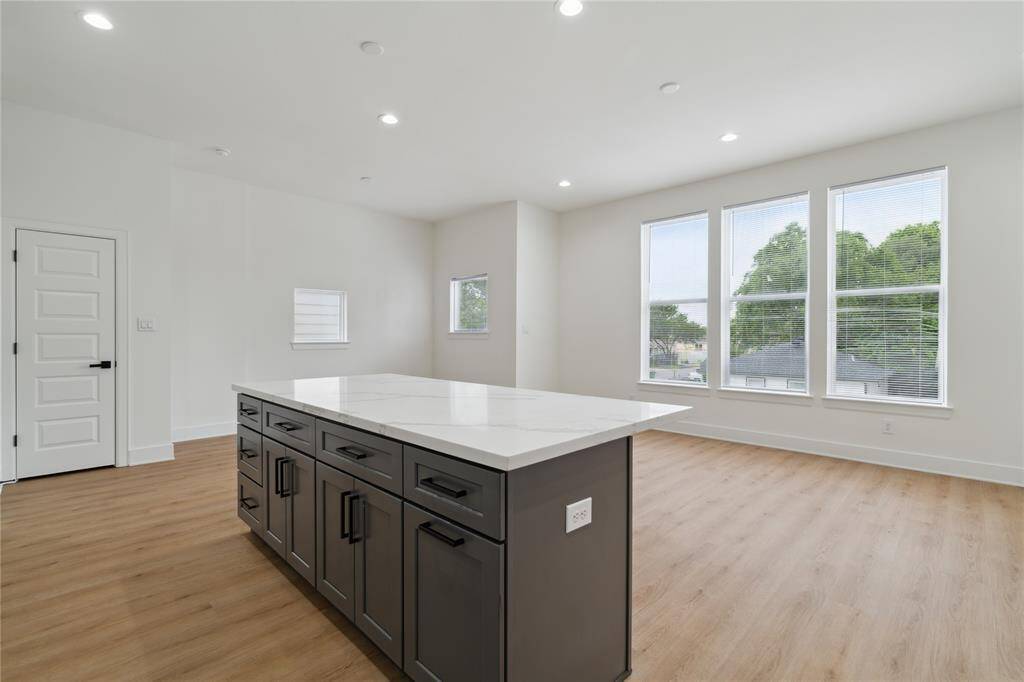 The kitchen seamlessly flows into the open living and dining area, bathed in natural light from large windows that create a bright and welcoming atmosphere. Perfect for both relaxing and entertaining