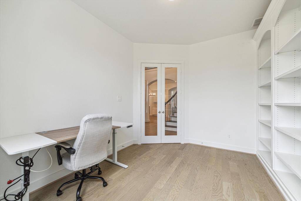The private Study features a wall of built in bookshelves, hardwood floors, and clear French double doors. Location is at the front of home so you can look out and see whats going on in the neighborhodd while still busy at work.