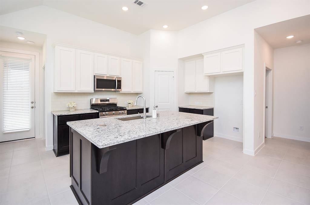 Classic white cabinetry and kitchen walls offer an instant sense of warmth in this space. Dark chocolate colored cabinetry is complemented by light granite counter tops and tile backsplash, wherever your tasks take you.