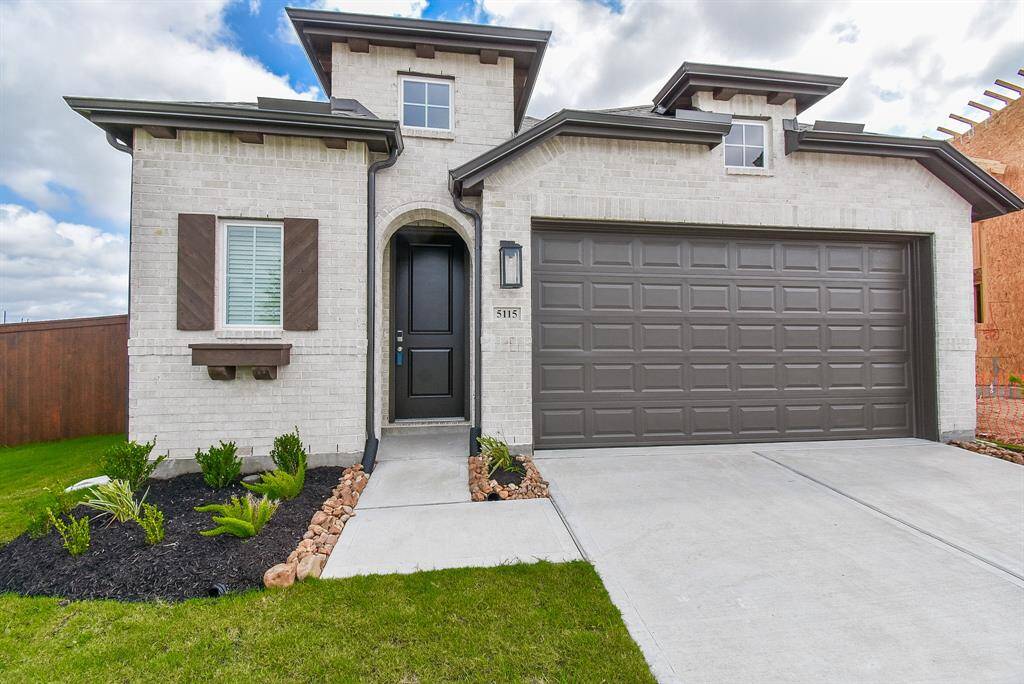 The dual vehicle garage sits atop a spacious driveway, with a pristine walking path leading to the covered front entrance.