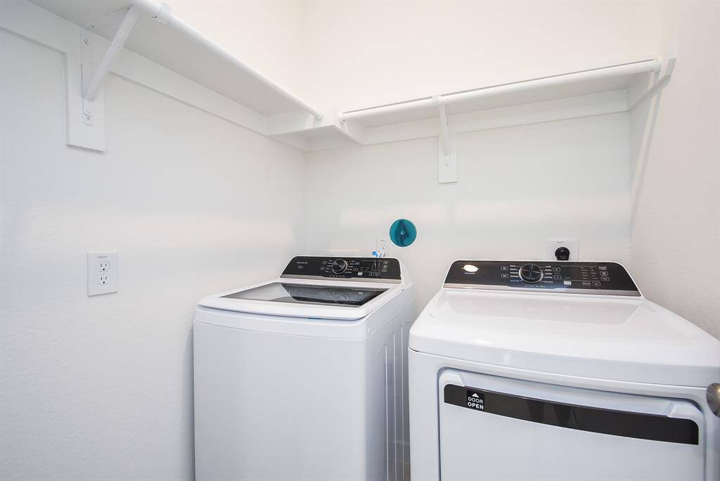 This bright utility room easily welcomes dual laundry appliances, with handy storage above.