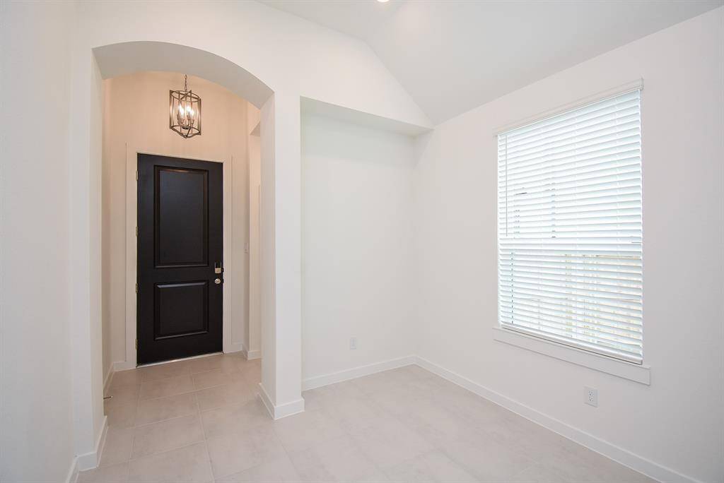 This is the bright, snow white front entry from the inside. Note the recessed wall niche, pale floor tiling, and one of many windows, bathing this area in pure natural light.