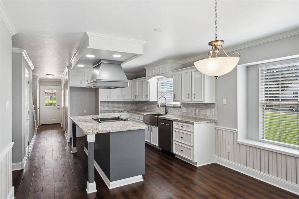 Updated kitchen has granite counters, stainless appliances, and white cabinets along with wood flooring.