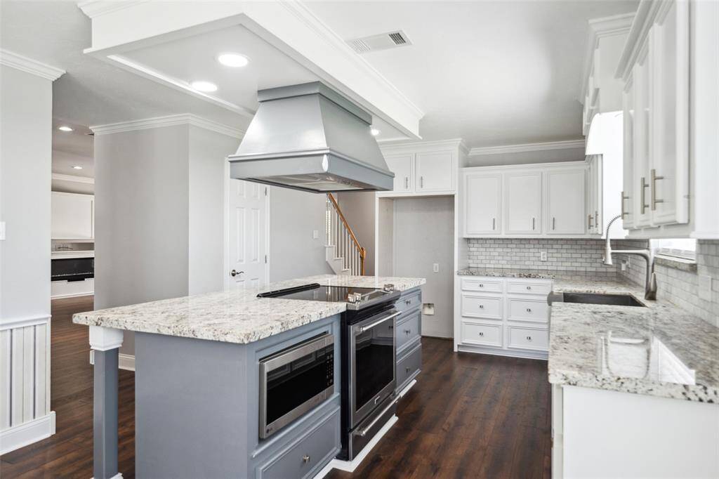 View inside the kitchen showing the oven/cooktop with hood, fand microwave oven.