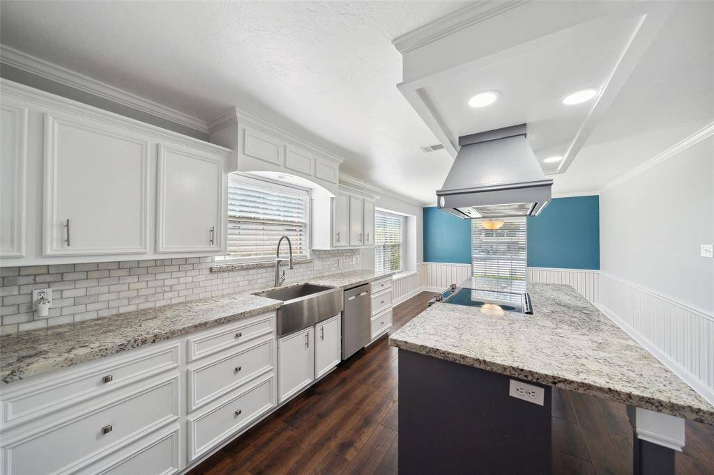 View of the stainless farmhouse sink, dishwasher, and window above the sink which lets in lots of natural light.