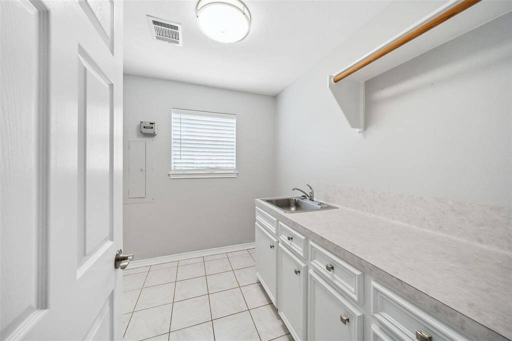 Laundry room has lots of counter space and cabinets along with a clothes hanging pole, and room for a small fridge. Washer and dryer go to the left around the corner, just out of view. Utility room also has a window to let in natural light.