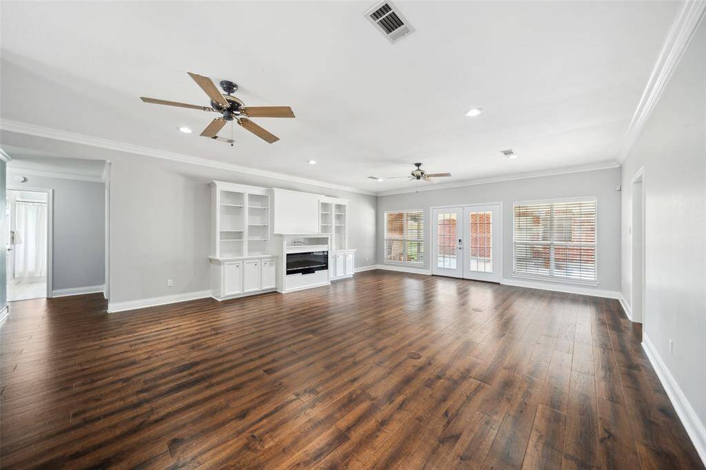 Large living area with built-in cabinets, wood flooring, and an electric fireplace. There are also two floor plugs here as well.