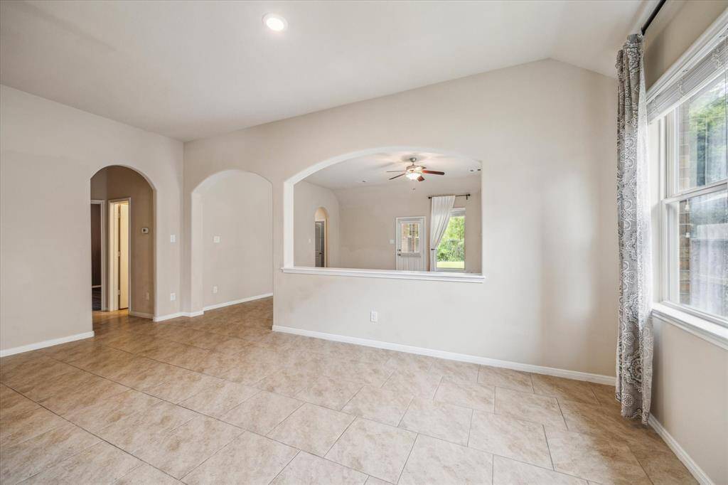 Bright and inviting dining area with elegant tile flooring, large windows for natural light, and charming archways providing separation between dining/kitchen and family room. Perfect for cozy breakfasts and family dinners.