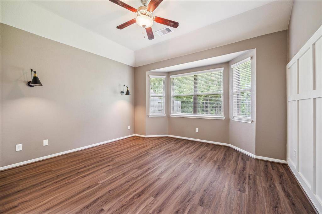 Elegant primary bedroom featuring exquisite wall molding, stylish sconces, and serene nature views.