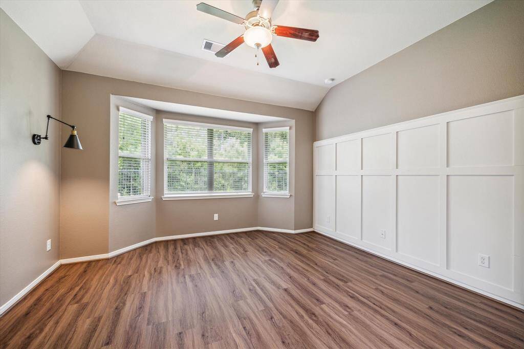 Elegant primary bedroom featuring exquisite wall molding, stylish sconces, and serene nature views.