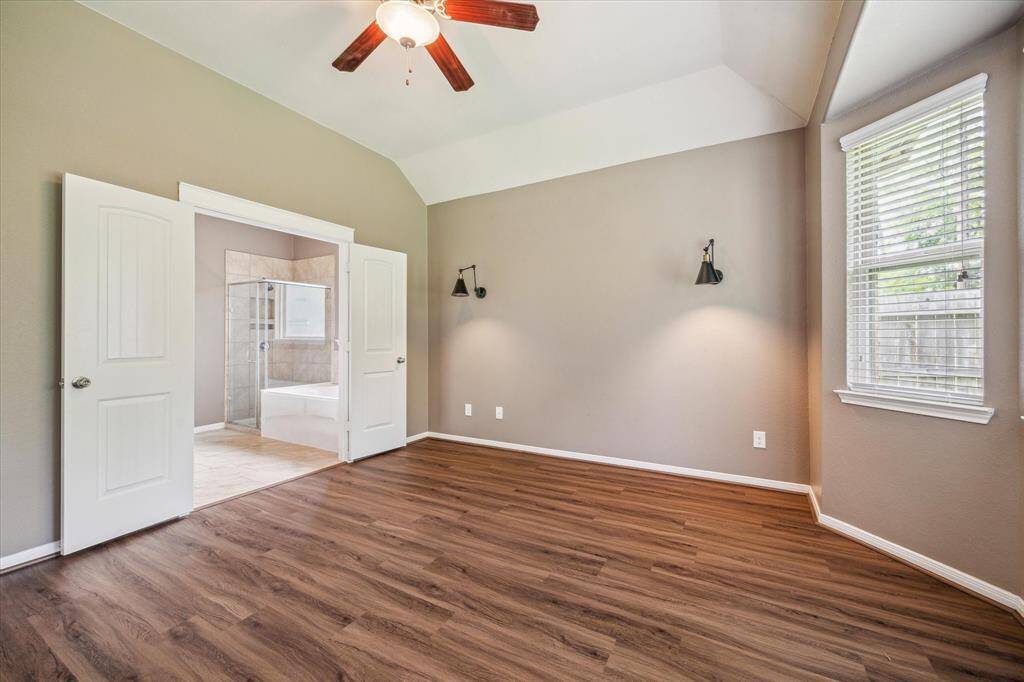 Elegant primary bedroom featuring exquisite wall molding, stylish sconces, and serene nature views.