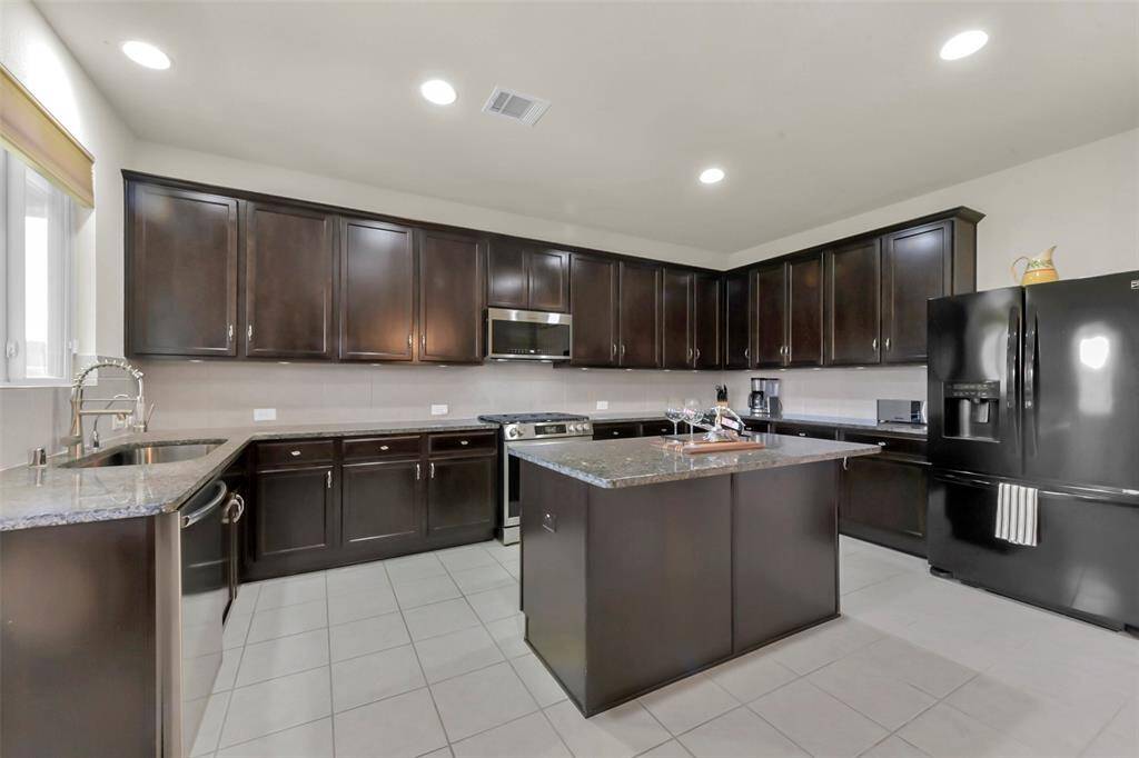 Step into the heart of the home – a beautifully appointed kitchen featuring rich brown cabinetry complemented by stylish hardware and beautiful appliances. The fantastic kitchen island serves as a central gathering point, perfect for casual meals with high chairs, offering a convenient alternative to the breakfast area