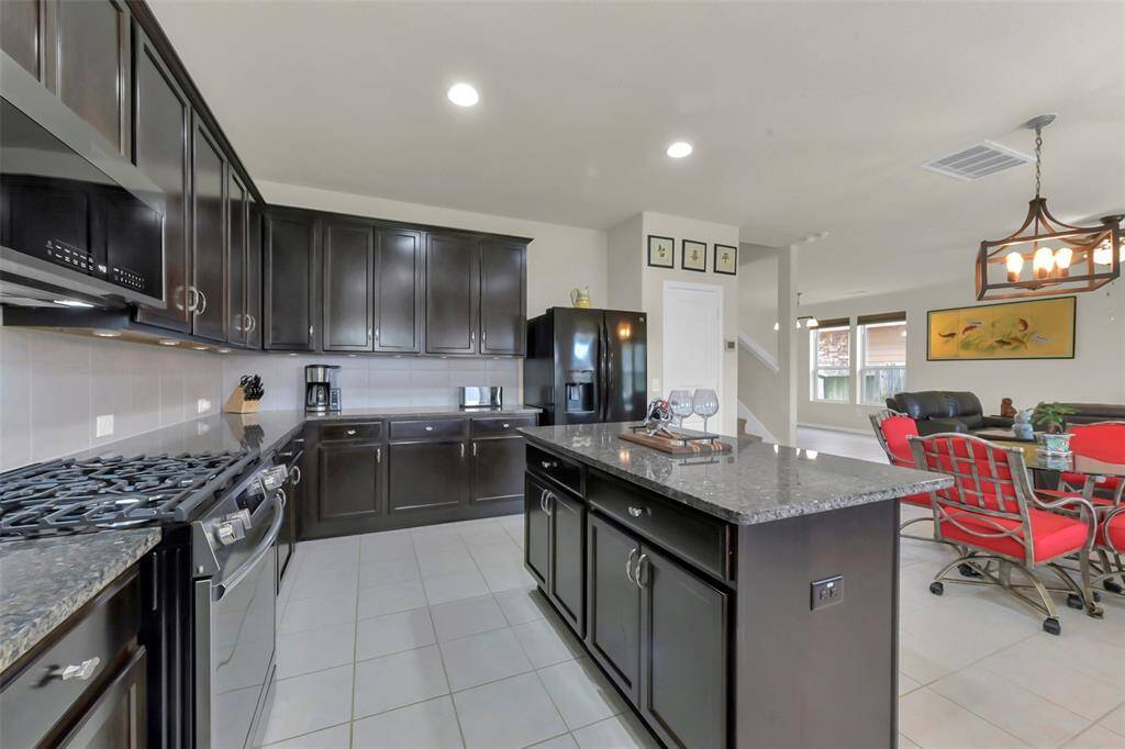 Step into the heart of the home – a beautifully appointed kitchen featuring rich brown cabinetry complemented by stylish hardware and beautiful appliances. The fantastic kitchen island serves as a central gathering point, perfect for casual meals with high chairs, offering a convenient alternative to the breakfast area.