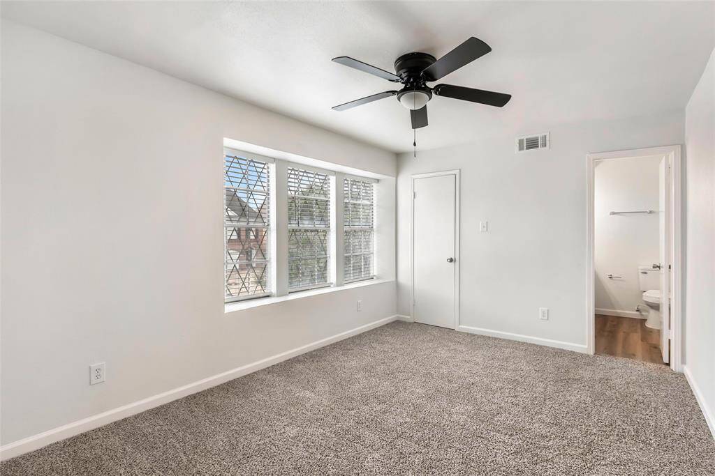 Spacious primary bedroom with abundant natural light, plush carpeting, and a private ensuite bathroom.