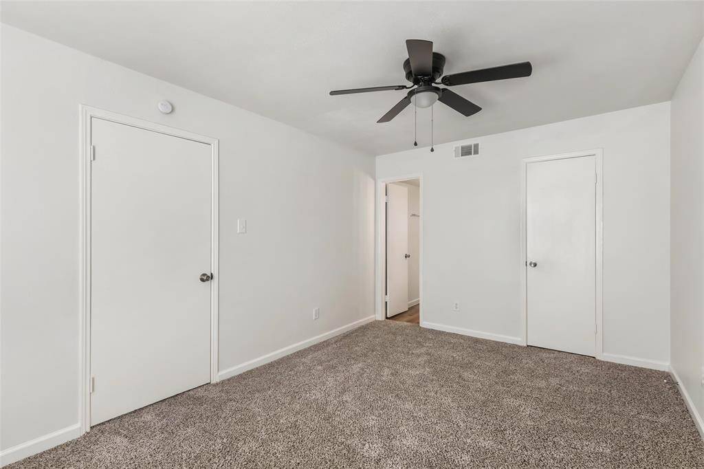 Cozy secondary bedroom with fresh neutral tones and plush carpeting, ideal for guests or a home office.