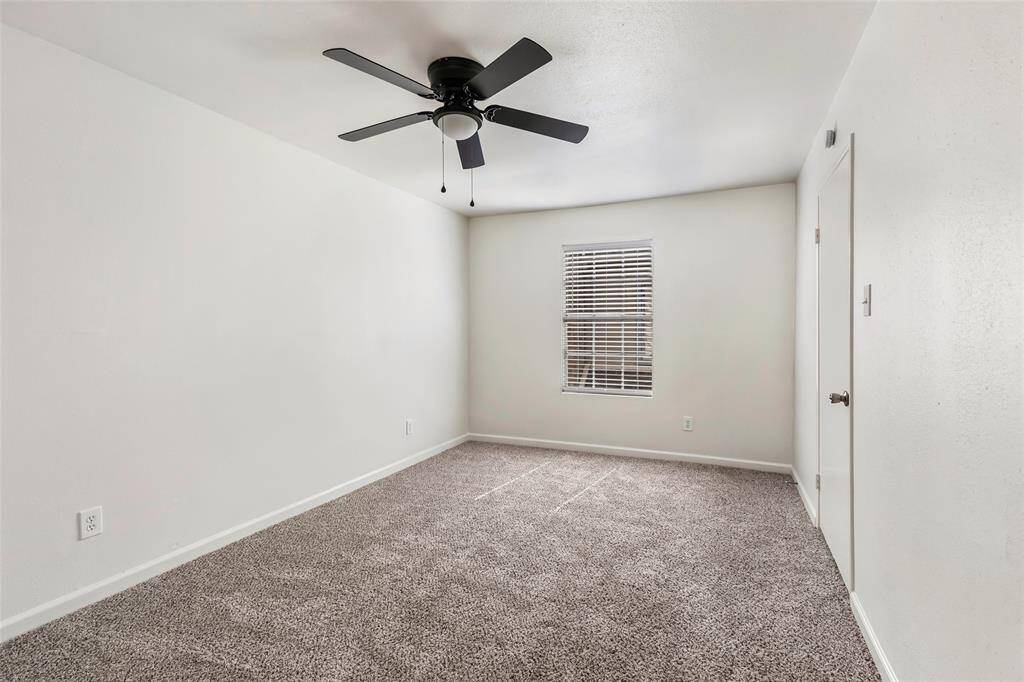 Spacious secondary bedroom with soft carpet, neutral walls, and ample natural light.
