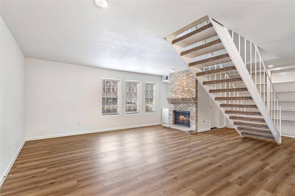 Discover your perfect retreat! This inviting living space boasts stylish flooring, a cozy fireplace, and an elegant staircase, offering comfort and charm in every corner.