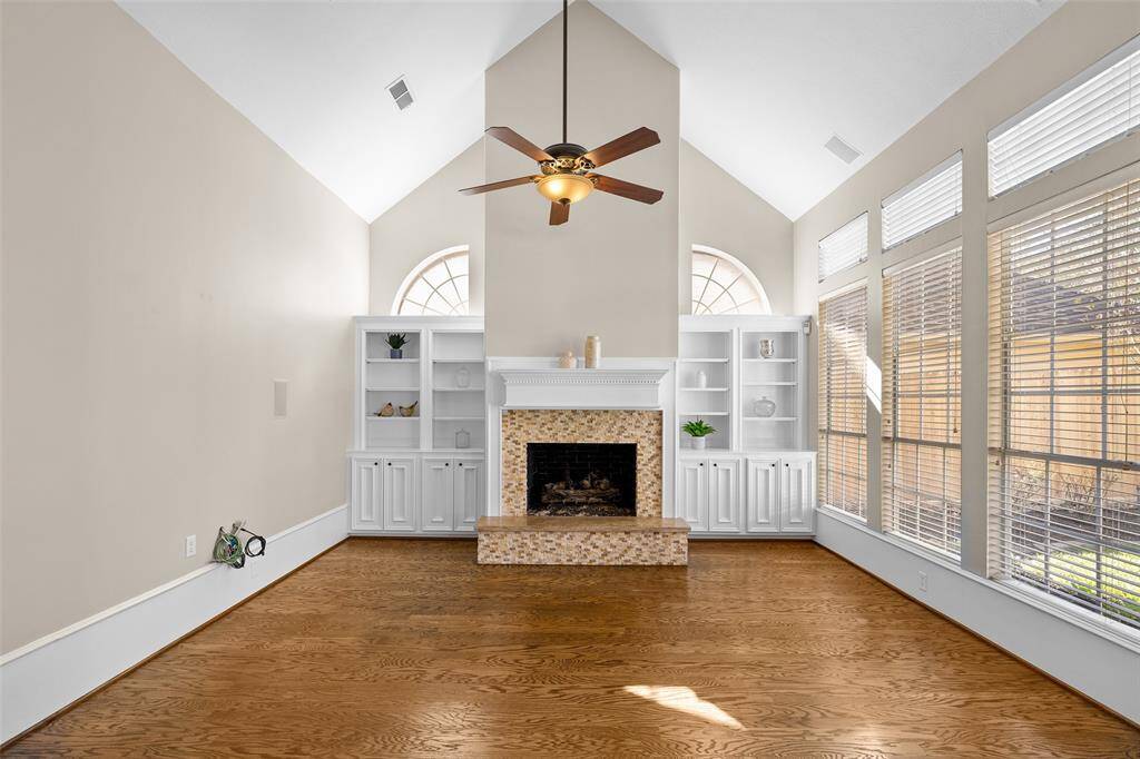 Gorgeous den with high vaulted ceiling and classic fireplace with decorative mantel.  Attractive built-in shelving on either side of fireplace provides ample space for display and storage.
