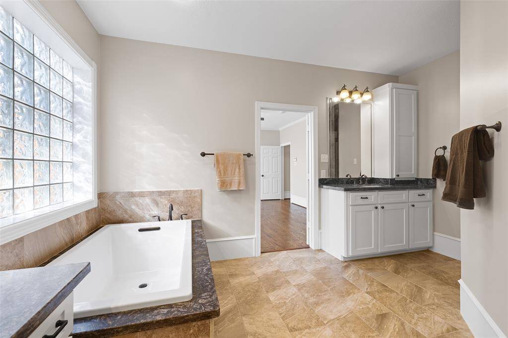 Another view of large primary bathroom with large glass block window providing plenty of natural light.