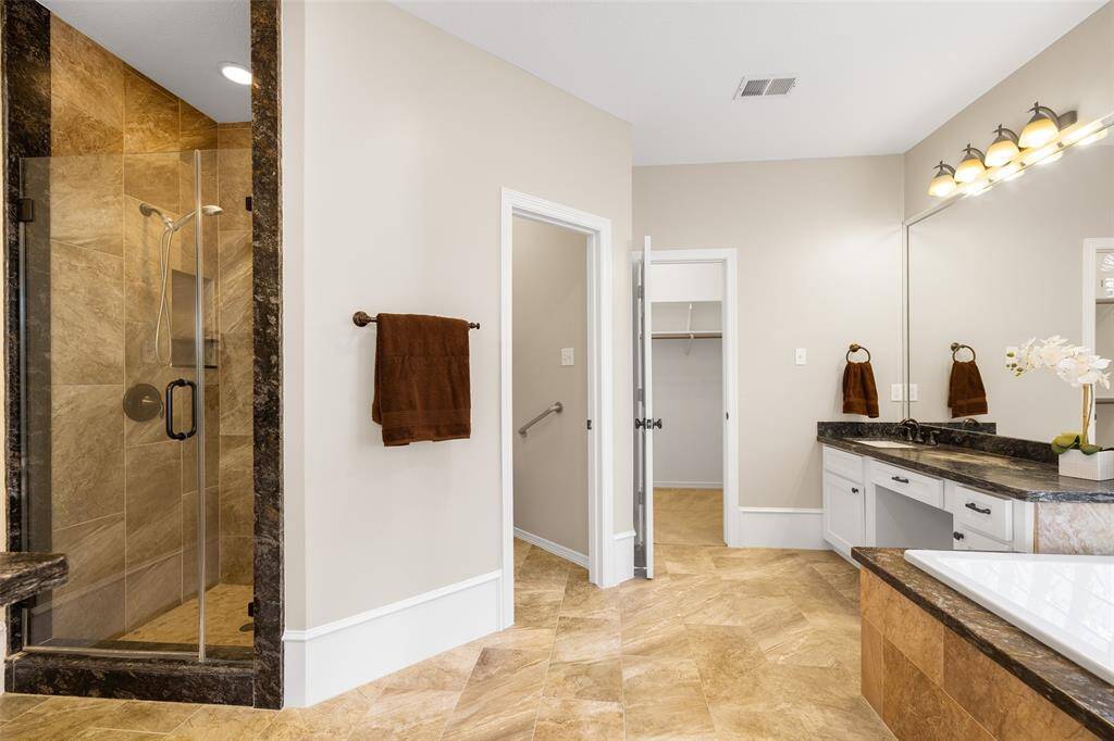 Beautifully updated primary bath with dual vanities and lovely stone walk-in shower.