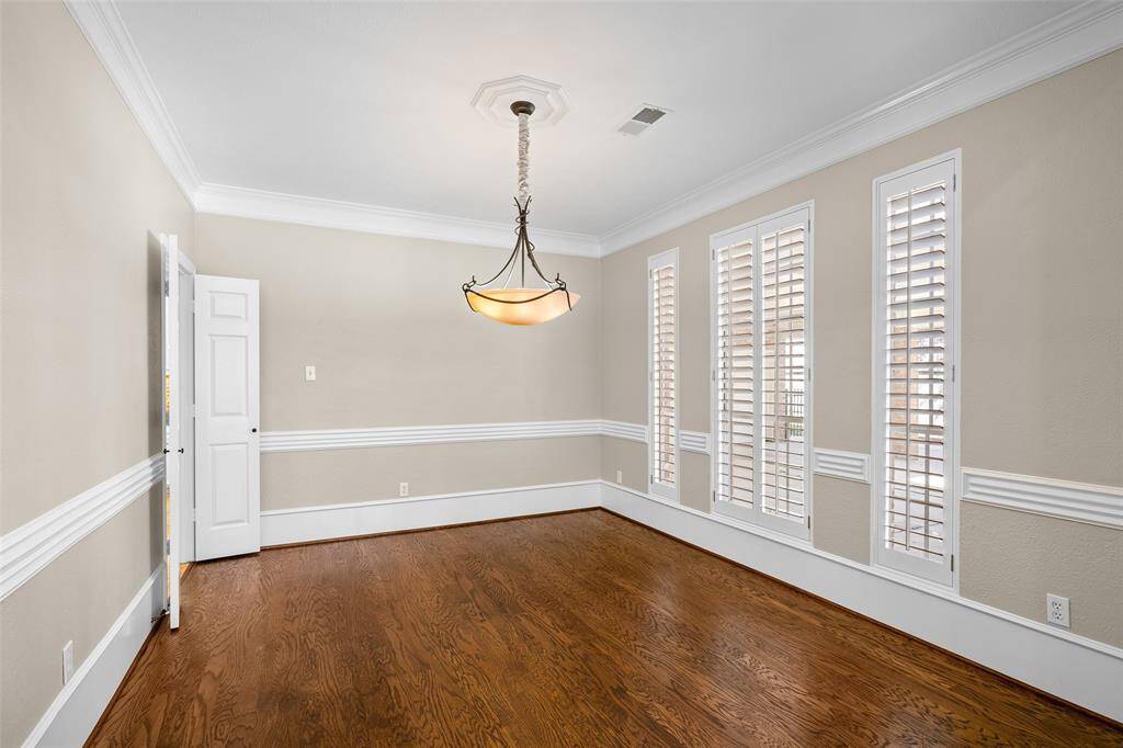 Large dining room with attractive chandelier and beautiful flooring shows entrance to kitchen.