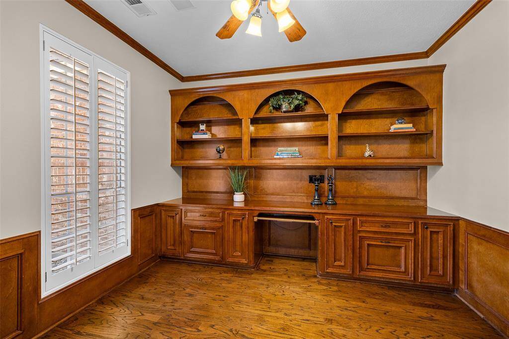 Large home office space featuring built-in wooden shelving, cabinetry and desk area creating a sophisticated space for work or study.